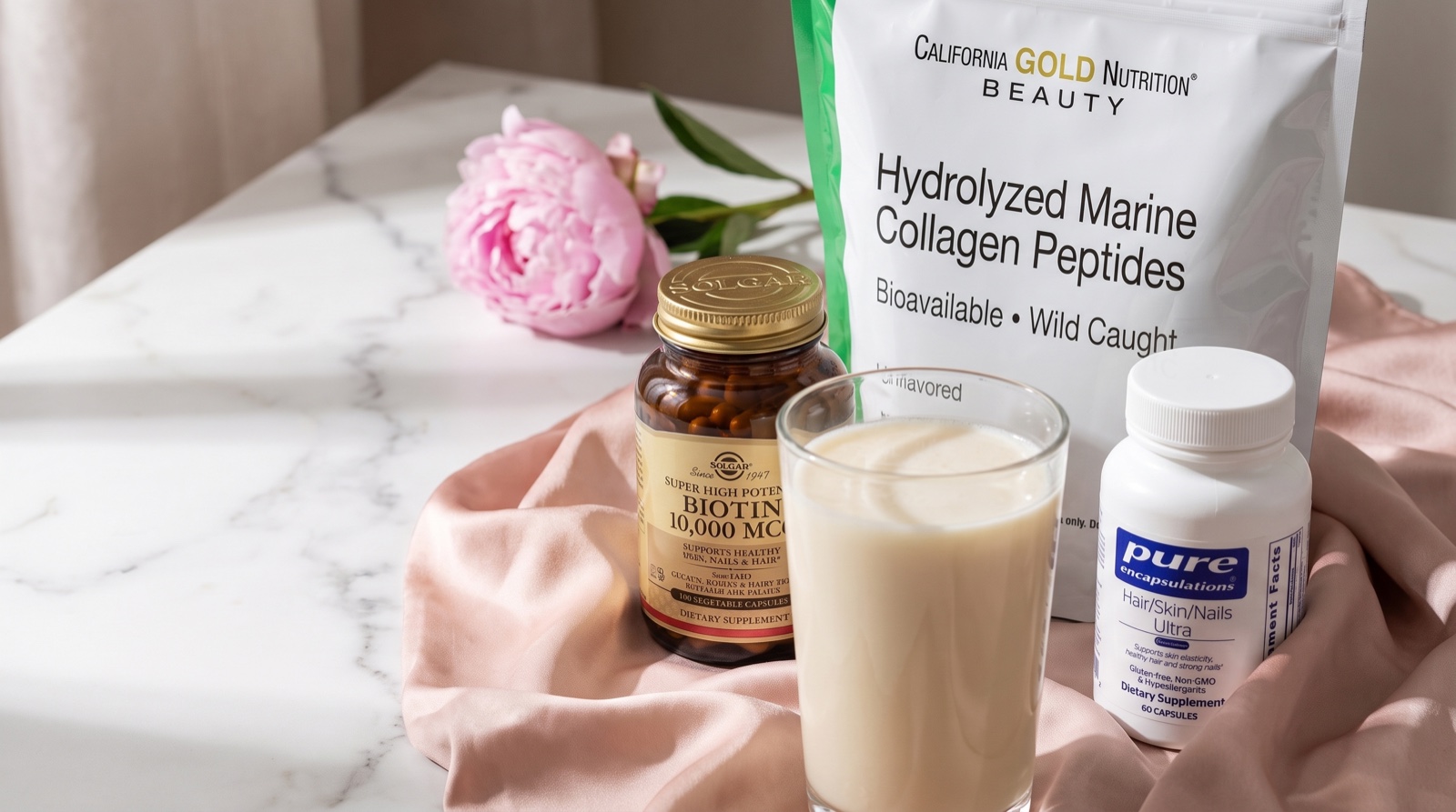 Морской коллаген California Gold Nutrition, биотин Solgar и Hair/Skin/Nails Pure Encapsulations на мраморном столике с пионом