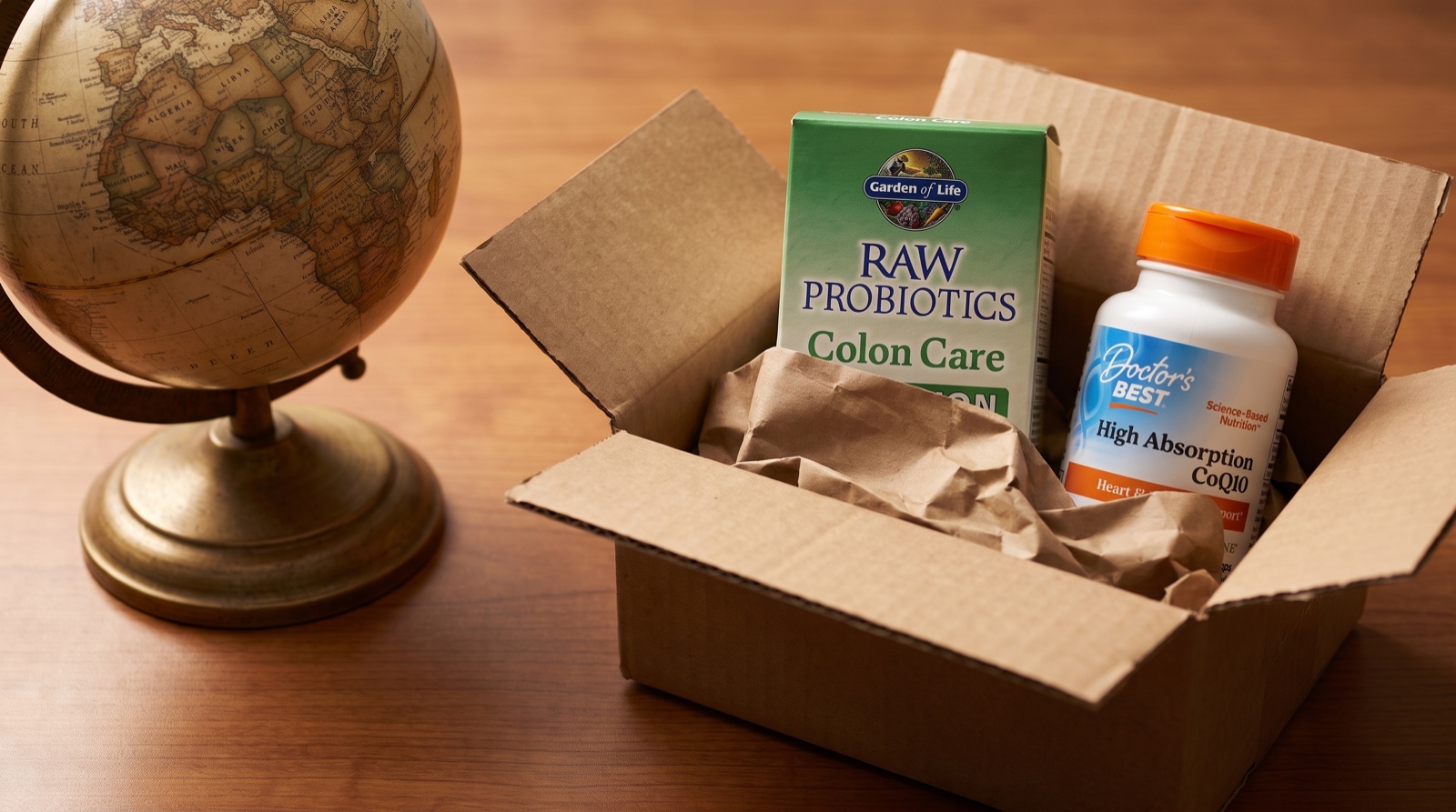 Открытая коробка с RAW Probiotics Garden of Life и коэнзимом Q10 Doctor’s Best рядом с глобусом