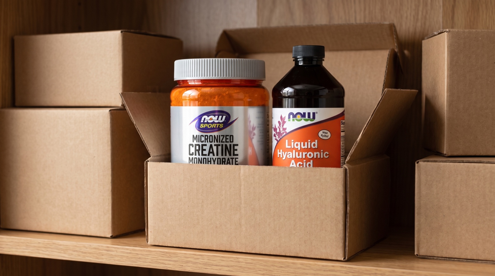 Креатин NOW Sports и жидкая гиалуроновая кислота NOW Foods в коробке на полке выдачи посылок